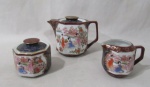 PORCELANA - MADE IN CHINA - Um bule, um açucareiro e uma cremeira em porcelana oriental vitrificada branca, com esmaltagem ricamente policromada e realces em douração, moldados em formato geometrizado, decorados com cenas de Gueixas e motivos vegetalistas, alças vazadas, pegas das tampas em forma estilizada de discos, bordas filetadas a ouro, marcados no fundo. Med. maior: alt total 12 cm x larg total 16 cm/ menor: alt total 8 cm x larg 8 cm.