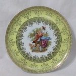 PORCELANA 541 PA - Um prato decorativo em fina porcelana europeia vitrificada branca, galeria central apresentando cena galante em rica policromia, seguido de guirlandas de flores, volutas e filetes em vasta douração, bordas adornadas com larga faixa esmaltada na tonalidade amarela e filetadas à ouro, marcado no fundo, medindo: 25,7 cm de diâmetro.