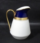 PORCELANA - STEATITA PARANÁ - Elegante leiteira em porcelana vitrificada branca, com bordas adornadas com largas faixas sendo na tonalidade azul cobalto, e gravação legitima, generoso filete e friso em pintura à ouro, alça vazada com vasta douração, marcada no fundo, medindo: alt 18,5 cm x larg total 13,5 cm.