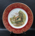 PORCELANA - KENYON - Prato decorativo em porcelana vitrificada branca, galeria central apresentando cena campestre ricamente policromada, bordas adornadas com larga faixa na tonalidade vinho, sobreposta com guirlandas de flores, volutas e arabescos em pintura à ouro, marcado no fundo, medindo: 27 cm de diâmetro.