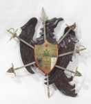 COLECIONISMO - Escudo de parede confeccionado em madeira entalhada representando águia, escudo com brasão em metal dourado com figuras realçadas, acompanha 5 espadas  e 2 lanças em metal, com descrição toledo. Medindo: 23 x 18 cm.