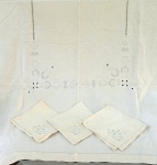 CAMA E MESA, uma (1) toalha retangular, confeccionada em linho na tonalidade creme com crivo e bordado Richelieu de ponto cheio na tonalidade cinza, acompanham 3 guardanapos na mesma padronização, medindo respectivamente 195 x 144 cm e 50 x 45 cm, usada e com manchas.