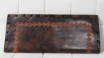 DIVERSOS - Uma (1) antiga carteiro em couro na cor marrom, decorada com flores e geométricos. Apresenta marcas de uso. Medida aberta 25,5 x 30 cm.