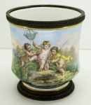 PORCELANA SÉVRES - Antiguissímo cachepot em porcelana francesa Sevrés, guarnecidos com base e aro em bronze e ao centro decorado com pintura de figura infantins - Med. 19,5x18 cm.