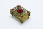 METAL - Porta caixa de fósforo em filigrana de metal dourado com aplicações de pedras coloridas. Med. 4x6x4 cm.