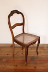 MOBILIÁRIO - Delicada cadeira em madeira nobre, assento em palhinha natural, encosto em madeira com detalhe em bronze, estilo inglês. Med. 89x42x40 cm.