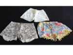 Três shorts juvenis n. 8 sendo um estampado com acabamentos de pedrarias, um branco bordado com pequeninas bonecas negras e um estampadinho.