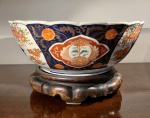 ARTE ORIENTAL - ANTIGO CENTRO DE MESA DE GRANDES DIMENSÕES EM PASTA DURA PADRÃO IMARI. BORDA ONDULADA E CORPO LEVEMENTE GOMADO. ACOMPANHA PEANHA CONFECCIONADA EM MADEIRA DURA, E ESCURA, PROVAVELMENTE BASE DE CEREJEIRA. JAPÃO, PERÍODO MEIJI. (1868 / 1912). MEDIDAS: 37,5 DE DIÂMETRO POR 15 CM DE ALTURA (SEM A PEANHA).