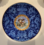 FAIANÇA ITALIANA / MAJOLICA - GRANDE ANTIGO MEDALHÃO COM 62,5 CENTÍMETROS DE DIÂMETRO APRESENTANDO RICA REPRESENTAÇÃO DO MITO GREGO; "TRIUNFO DE GALETEIA". SEGUNDA METADE DO SÉCULO XIX. ESTE GFANDE MEDALHÃO RETRATA A CENA NA QUAL GALETEIA RETORNA TRIUNFANTE APÓS LIBERTAR-SE DO CICLOPE. A GALERIA DA PEÇA É PROFUSA E RICAMENTE DECORADA EM ESMALTAGEM E FINA PINTURA EM TONS DE AZUL MARINHO RETRATANDO FIGURAS MITOLÓGICAS QUE ALUDEM A BATALHA PELA LIBERTAÇÃO DA PERSONAGEM. PONTOS DE FALHAS NO PROCESSO DE ESMALTAGEM (VISÍVEIS NAS FOTOS). MEDIDAS: 62,5 X 9,5. FIXAÇÃO POSTERIOR FEITA POR SUPORTE DE METAL.  NOTA: Galeteia na mitologia grega, é uma nereida, filha de Nereu e Dóris. Andava em uma carruagem puxada por golfinhos. Seu nome significa "donzela branca". Vivia nas costas da Sicília. Passava seu tempo brincando nas ondas do mar. Galateia se apaixonou-se pelo pastor de ovelhas de nome; Ácis. Na sequência a jovem foi avistada pelo ciclope Polifemo, que se apaixonou por ela. Este era um dos temíveis e monstruosos ciclopes, gigantes de um só olho, que habitavam aquela ilha. Galateia, porém, era enamorada do belo Ácis, filho do deus Pã e de uma ninfa. Um dia, quando a nereida repousava com seu amante junto ao mar, ambos foram vistos por Polifemo. Este perseguiu Ácis e terminou por esmagá-lo com uma enorme rocha, e sequestrou a nereida para desposa-la. Após longa 'batalha' para libertar-se e voltar para 'casa' Galateia reviveu seu amado convertendo-o em um rio de águas límpidas, apelando para a mãe deste, uma ninfa dos rios. Em seguida, lançou-se ao mar indo viver nas ondas que tocam as areias com suas espumas brancas, sem retornar à terra.