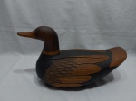 Enfeite na forma de pato em madeira entalhada, assinada "Valdemar e Roberto". Medindo 45cm x 18cm x 27cm de altura.