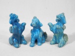 Três esculturas em porcelana na cor azul representando poodles. Uma delas apresenta quebrado. Alt. do maior 7 cm.