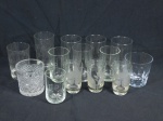 Quinze copos diversos em vidro translúcido. Um deles apresenta bicado na borda. Alt. do maior  13 cm.