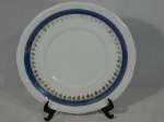 Prato para bolo em porcelana nacional branca, borda com decoração em alto relevo, faixa azul e flores em douração. Marcado "Schmidt". Diam. 27,5cm.