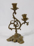 Castiçal em bronze para duas velas, base e haste decoradas com volutas e folhagens. Alt. 26cm.