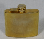 Garrafa para bebida em metal dourado decorada com escudo, capacidade para 150ml. Med. 9,5 x 9,5 x 2cm.