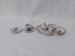 Lote de miniaturas em porcelana, sendo um conjunto de chá com bandeja, uma xícara e um pratinho. Medindo a bandeja 14cm x 9cm.