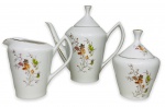 POZZANI -  Trio de parte de serviço para café, contendo 3 peças sendo, um bule, uma leiteira e um açucareiro em porcelana branca esmaltada, ricamente adornada com motivo floral em policromia e contorno em vibrante ouro. Acompanham suas respectivas tampas com pega. Possuem registro da manufatura POZZANI JUNDIAI na base. Medida do maior 19cm de altura x 21cm de comprimento.