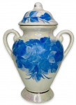 EUROPA - Elegante potiche no formato de ânfora em porcelana branca esmaltada ricamente adornada com motivo floral na cor azul, pintado a mão e contorno em prata. Acompanha sua respectiva tampa. Possui discreto fio de cabelo na tampa. Mede 22cm de comprimento x 29cm de altura.