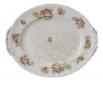 ENGLAND - Delicada travessa em fina porcelana inglesa na cor creme, adornada com flores em policromia, fios de ouro e borda ondulada. Imperceptível bicado no verso. Possui registro da manufatura na base. Mede 21 x 26 cm.