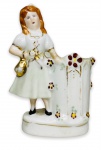 EUROPA 1900 - Delicada floreira em porcelana européia esmaltada, adornadas com detalhes em policromia e vibrante ouro, representando figura de dama portando bolsa. Mede 10 x 8cm.