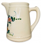 Antiga leiteira em porcelana branca esmaltada ricamente adornada com motivo floral em policromia. Apresenta sinais de restauro. Marcas do tempo. Numerada na base. Mede 19cm.
