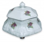 PEDREIRA - Elegante porta-joias em porcelana branca esmaltada ricamente adornado com motivo floral em policromia e resquícios de contorno em vibrante ouro. Acompanha sua respectiva tampa com pega. apoiada sobre três pés. Possui registro da manufatura na base. Mede 9cm de altura x 12cm de comprimento.