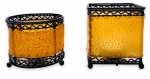 INDIA - Duo de elegantes porta velas indianos, com estrutura em metal patinado, sendo um no formato arredondado e outro quadrangular. Acompanham suas respectivas velas. Apoiados sobre três pés no formato de bola. Medida do maior 9cm.