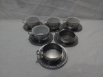 Jogo de 4 xícaras de chá em porcelana com 6 suportes e pires em aço inox. Sendo uma das xícaras com bicado.