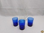 Lote de jarra em vidro incolor com base quadrada e 3 copos em vidro azul cobalto. Medindo a jarra 21cm de altura.