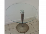 Mesa de apoio com tampo de vidro sustentada por haste  apoiada em base circular com marcas de oxidação. Alt. e Diam. 60 cm.