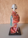 Antiga gueixa da década de 90. Suas roupas são ricamente trabalhadas com tecidos típicos  japoneses. Rosto, mãos e pés de material não  identificado e cabelos de material sintético.  Base de material muito parecido com MDF. possui um pequeno descascado no nariz, sem restaurações. A peça se encontra em bom estado de conservação como se vê nas fotos.