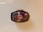 Antiga caixa para pílulas, ou rapé, feito em arte cleizonné, com detalhes em bronze. Altura: 1cm; Comprimento: 3,5cm; Largura: 2,5cm.