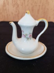 Antiga miniatura de bule de chá com pires. O item possui é pintado a mão e está em perfeito estado de conservação.  Tendo o bule 7cm de altura e 3cm de largura, o pires tem 8cm de diâmetro.