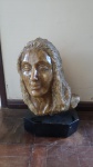 Busto feminino de mármore entalhado na cor de citrino. Sua base feita em granito preto e o item possui gira em ângulo de 360º. Sua altura é de 50 cm, sua largura é de 30cm, a profundidade é de 20cm e pesa aproximadamente 50kg.
