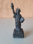 Réplica da estátua da liberdade com apontador. A peça é feita de antimônio e apresenta alguns desgastes do tempo. Altura: 9cm; Largura: 2,5cm.