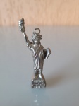 Pingente da estátua da liberdade em metal prateado. Altura: 6,5cm; Comprimento: 1,5cm.