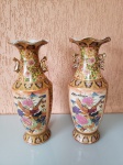 Antigo par de vasos japoneses. As peças são idênticas, tirando as alças que possuem uma pequena diferença. O item é extremamente detalhado, possuindo folha de ouro e pintura feita a mão, com relevo. As peças estão em perfeito estado de conservação.  Tamanho - Boca: 16cm; Altura: 46cm; Diâmetro da base: 14cm.Obs: Contate para mais fotos, pois a peça é ricamente detalhada.