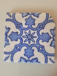 Antigo azulejo português do século XIV. O item possui desenhos simples na cor azul com fundo branco e desgaste nas bordas. Tamanho: 15,5X15,5cm