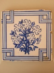 Antigo azulejo espanhol com desenho azul de flores no meio e desenhos geométricos nas bordas. A peça é oriunda de demolição de casarões do Rio de Janeiro e está em bom estado, porém possui pequenos e poucos bicados. Altura: 1,3cm; Dimensões: 20cmX20cm.