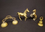 Quatro peças em metal dourado, sendo: duas esculturas de cavalos, sineta dupla e sino. Med. cavalo maior: Alt. 17 x 19 x 4cm. e med. sino (Alt. 10 x Diam. 5,5cm).