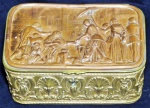 Caixa de coleção europeia em cobre, ricamente cinzelada por volutas, folhagens e concheados, 4 pés em fetio floral, com cenas de figuras em relevo. 7x18,5x11,5cm.