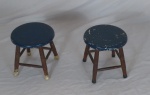 Duas banquetas baixas em madeira nobre com assento pintado de azul (folhas na pintura). Uma delas com selo do fabricante. SOUZA MARTINS. Med.: 28x26cm.