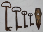 Quatro antigas chaves de coleção (8,5cm / 11,5cm / 15,5cm e 19cm). Acompanha antiga ferramenta em ferro fundido. Med.: 14cm.