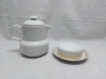 Lote composto de bule e manteigueira em porcelana. Medindo o bule 14,5cm de altura. Leve fio de cabelo no bule.