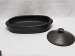 Travessa oval em barro com patina preta, acompanha uma tampa redonda com bicado. Medindo a travessa 39cm x 22cm x 6,5cm de altura.