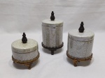 Jogo de 3 potiches em porcelana com pé e alça em metal dourado. Medindo o maior 8,5cm de diâmetro x 12,5cm de altura.