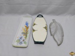 Lote composto de 2 petisqueiras em porcelana e 1 petisqueira em vidro na forma de folha. Medindo a maior 39cm x 13,5cm.