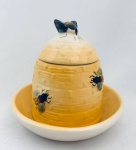 Porta mel confeccionado em faiança, com espaço para colocar água que evita a entrada de formigas, decorado com abelhas em relevo. Med. 14x14 cm.