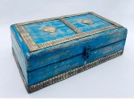 Caixa em madeira patinada na cor azul, tampo decorado com aplicações em metal dourado em relevo. Fecho com espaço para colocação de pequeno cadeado. Med. 24x13x7 cm