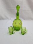 Jogo de pequena licoreira com 2 copinhos em vidro verde canelado. Medindo a licoreira 20cm de altura e os copinhos 5cm de altura.